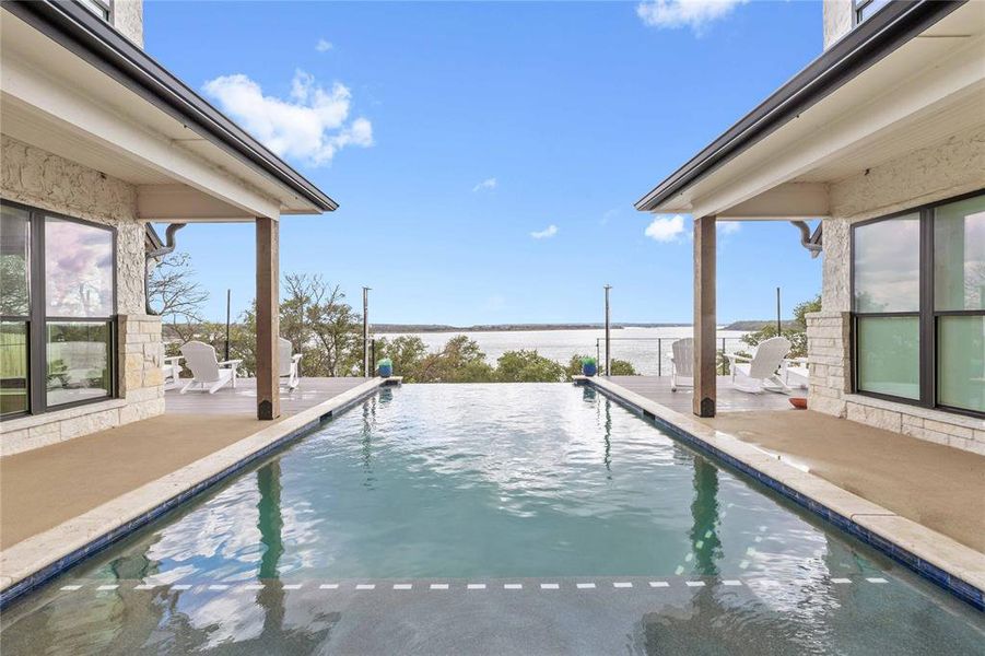 View of pool featuring a patio area, an infinity pool, and a water view