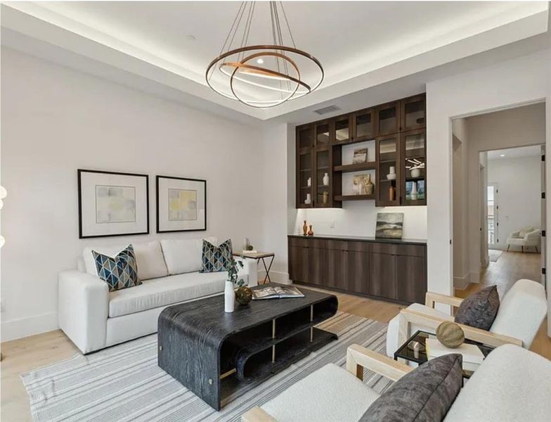 Living room with light wood-type flooring, a raised ceiling, and recessed lighting