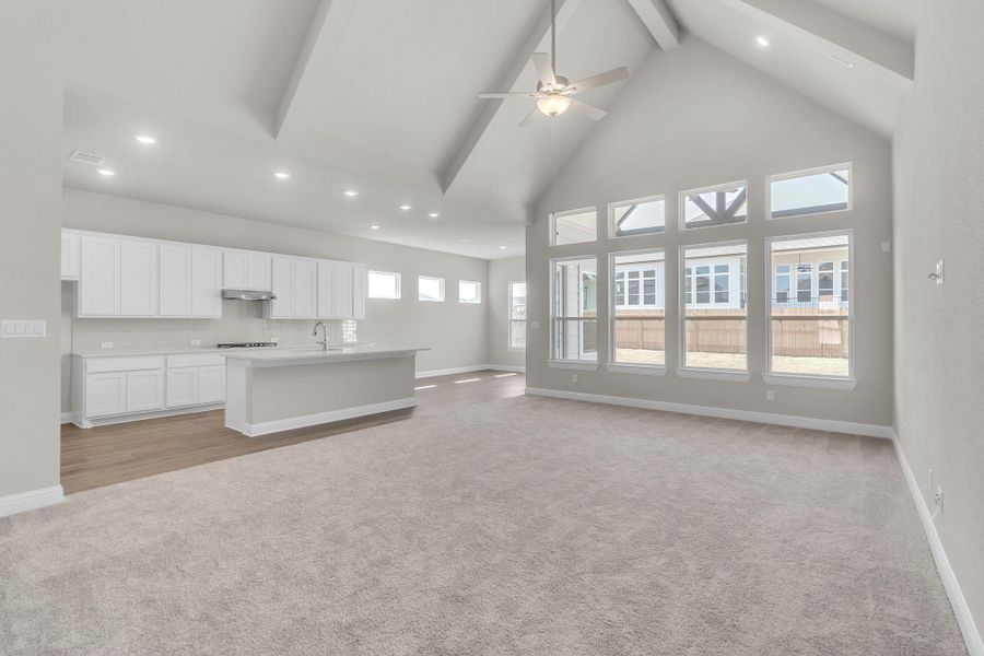 Unfurnished living room with baseboards, beam ceiling, light carpet, high vaulted ceiling, and a sink Unfurnished living room with baseboards, beam ceiling, light carpet, high vaulted ceiling, and a sink