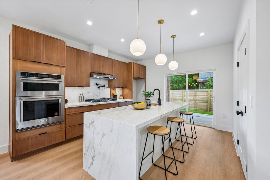 A well-lit kitchen with elegant wood cabinetry, quartz countertops, and sleek stainless steel appliances.