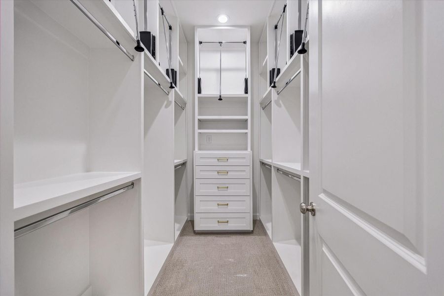 Walk-in customized primary closet - offering stainless steel rods, built-in drawers and pull-down rods.
