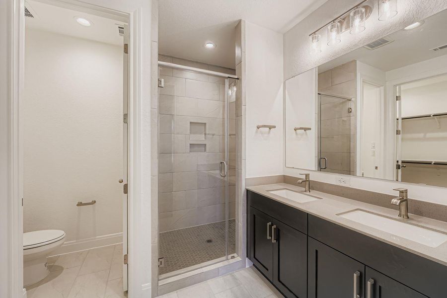Full bath featuring a shower stall, double vanity, recessed lighting, and a walk in closet