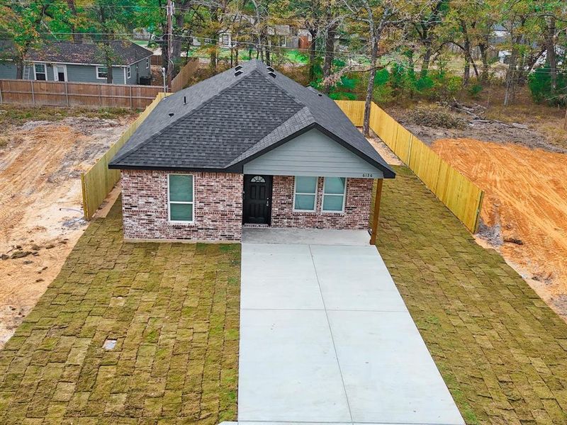 View of front of property featuring a shingled roof, brick siding, and concrete driveway