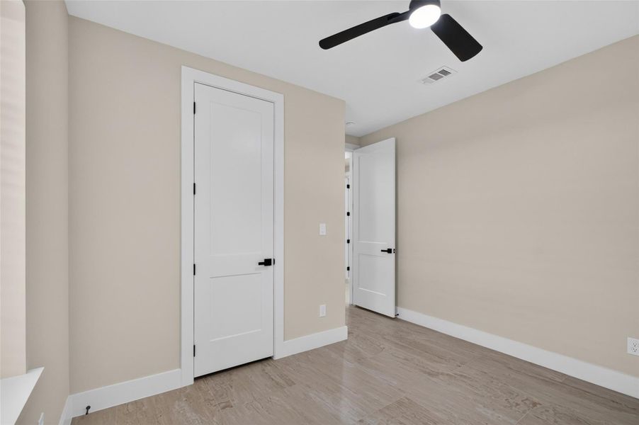Bright, modern room with sleek wood flooring, neutral walls, and a contemporary ceiling fan, offering a clean and fresh atmosphere.