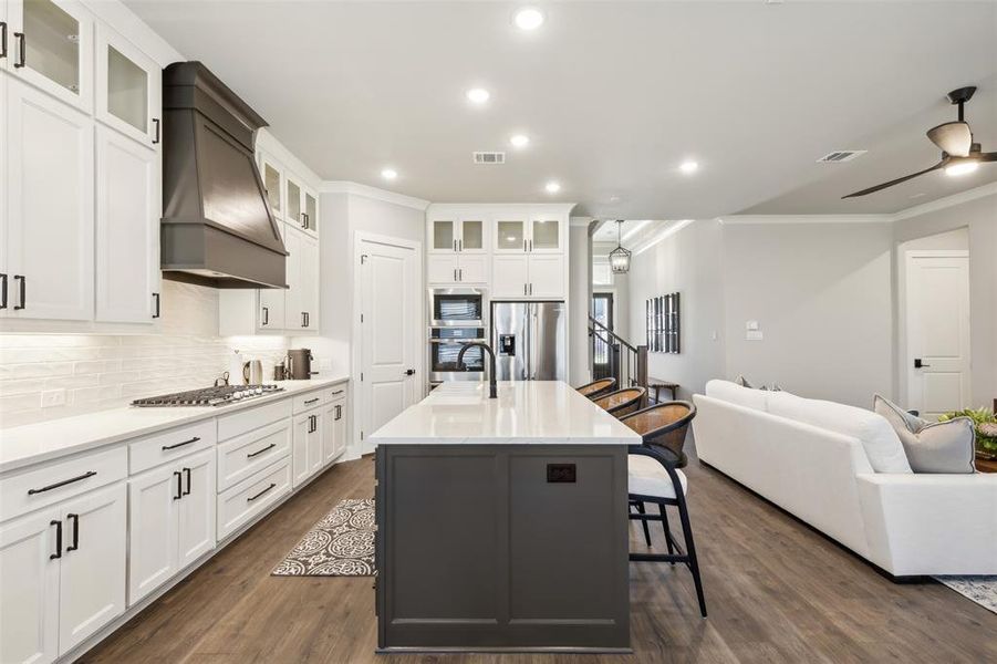 Kitchen with a breakfast bar, a kitchen island with sink, appliances with stainless steel finishes, dark hardwood / wood-style flooring, and custom range hood