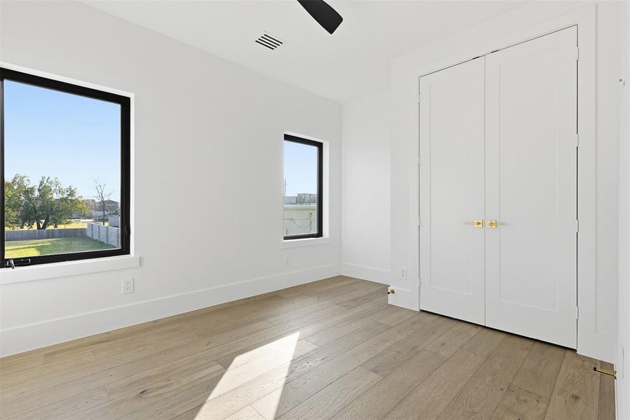 Same floorplan - different finishes. Spacious bedroom featuring dual-swing closet doors with modern gold lever handles and minimalist white trim.