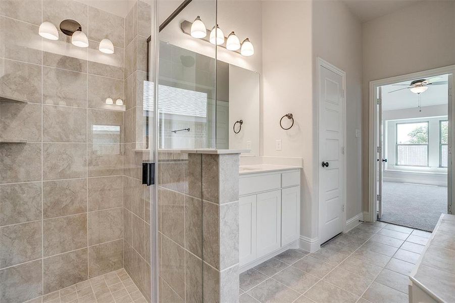 Bathroom featuring tile patterned floors, vanity, a tile shower, and ceiling fan