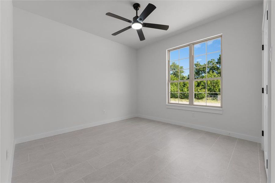 Tiled spare room featuring ceiling fan