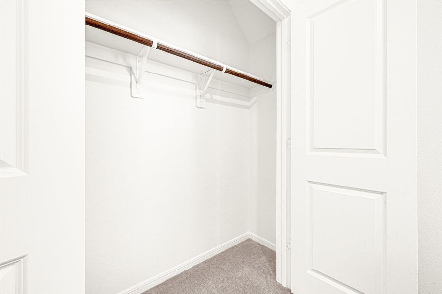 Close-up view of the functional walk-in closet space, complete with standard wire hanging racks.