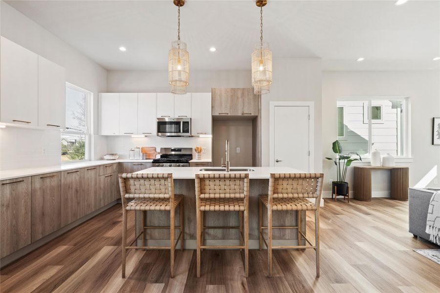 A wide, functional island anchors the kitchen, surrounded by generous storage and a clean, understated backsplash that keeps the space feeling light and intentional.