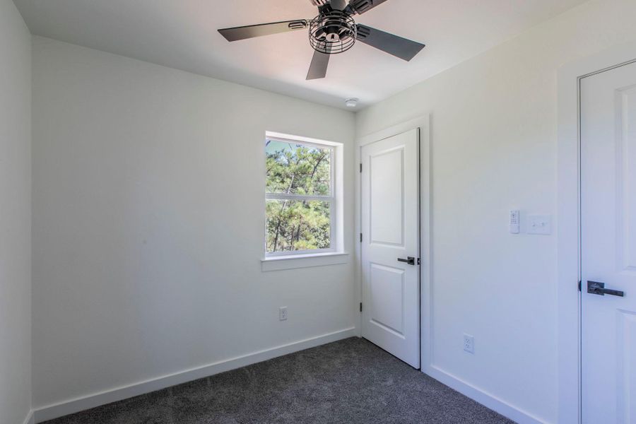 Unfurnished bedroom featuring dark carpet and ceiling fan