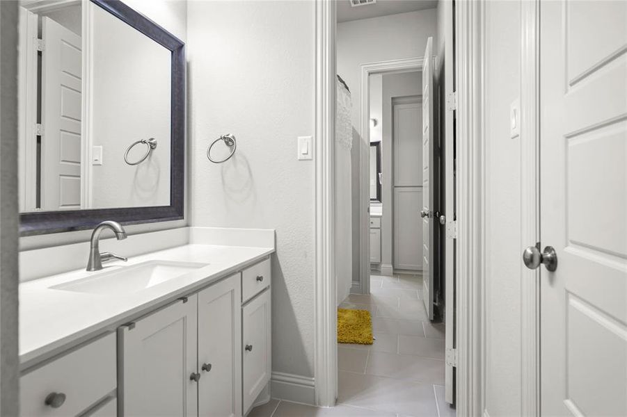 Bathroom featuring vanity, light tile patterned floors, and a textured wall Bathroom featuring vanity, light tile patterned floors, and a textured wall