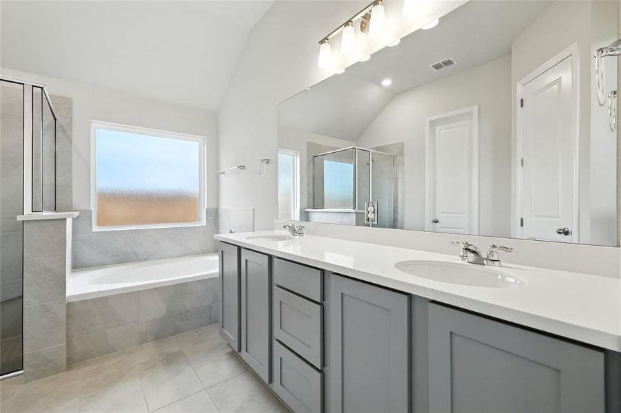 Full bath with a shower stall, vaulted ceiling, a bath, double vanity, and light tile patterned floors Full bath with a shower stall, vaulted ceiling, a bath, double vanity, and light tile patterned floors
