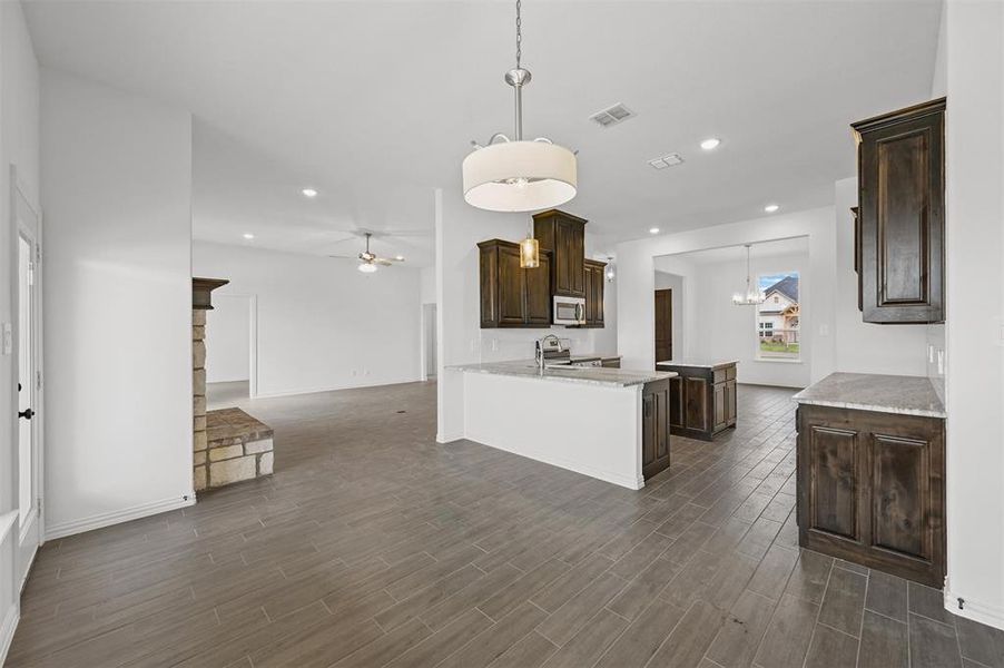 Kitchen with stainless steel appliances, decorative light fixtures, kitchen peninsula, and dark hardwood / wood-style flooring