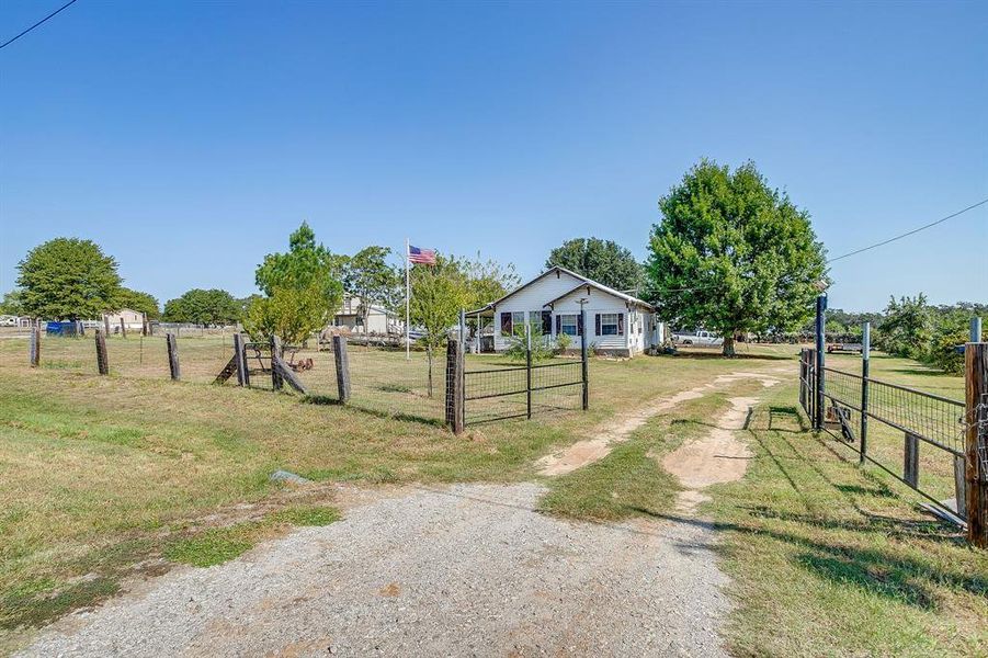 View of dirt / gravel road with a gated entry, a gate, and a view of countryside View of dirt / gravel road with a gated entry, a gate, and a view of countryside