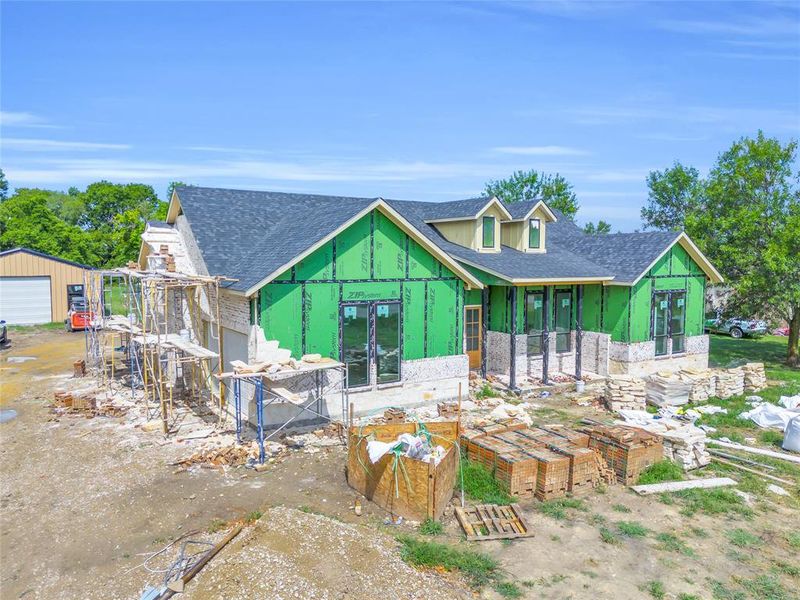 Rear view of property with a shingled roof, an outdoor structure, and stone siding Rear view of property with a shingled roof, an outdoor structure, and stone siding