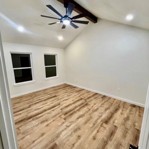A well-lit bedroom with vaulted ceilings and rich wood flooring awaits personalization.