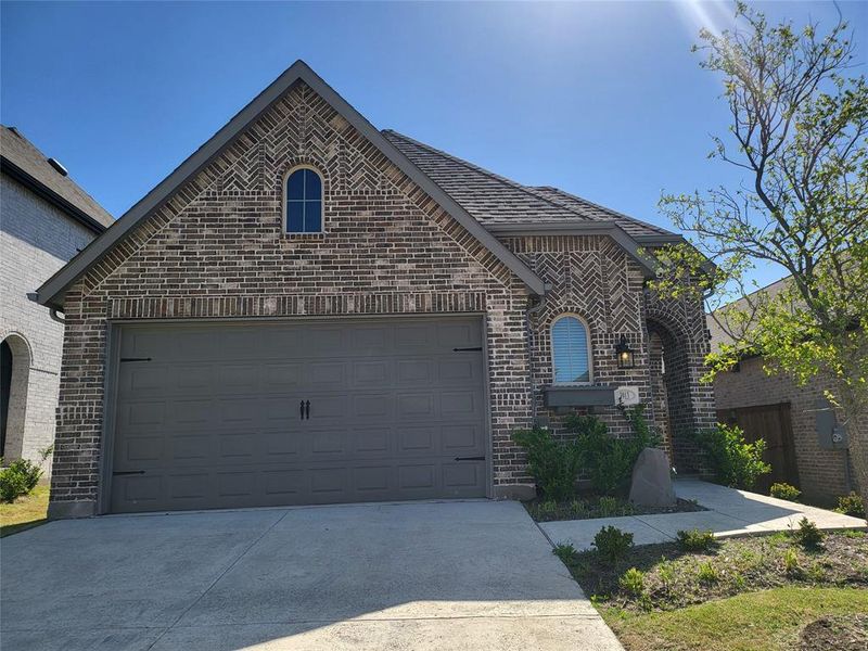 French country home with concrete driveway, brick siding, and a garage French country home with concrete driveway, brick siding, and a garage