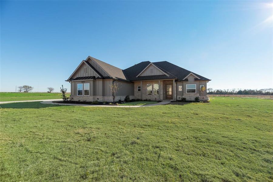 View of front of home featuring a front yard, board and batten siding, and brick siding View of front of home featuring a front yard, board and batten siding, and brick siding