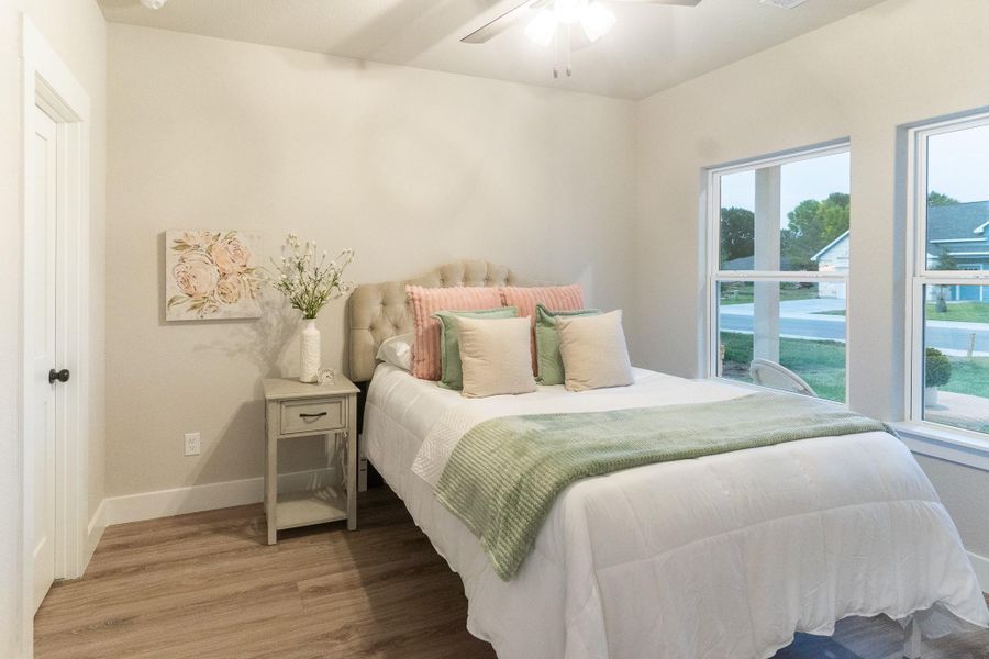 Bedroom with light wood finished floors, baseboards, and ceiling fan