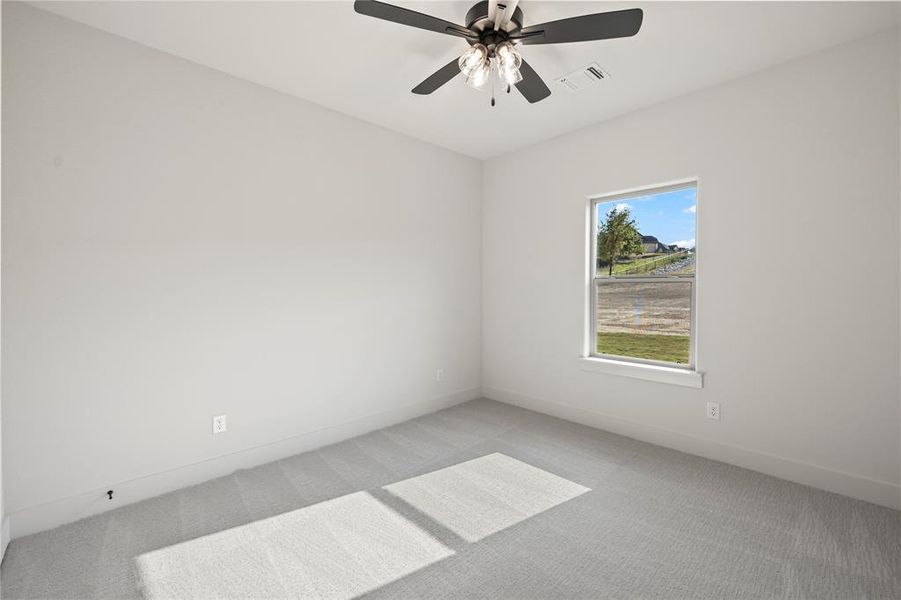 Carpeted spare room with baseboards and a ceiling fan
