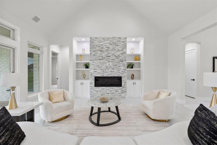 Living room featuring built in features, high vaulted ceiling, a large fireplace.