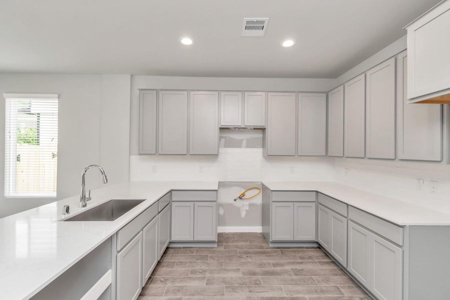 Culinary haven, featuring granite countertops, a tile backsplash, stainless steel appliances (to be installed), and 42” upper cabinets. Sample photo of completed home with similar floor plan. Actual colors and selections may vary.