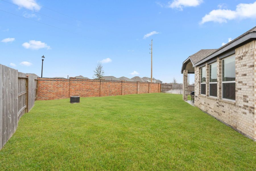 Generous yard space surrounds the home, providing flexibility for future landscaping, play equipment, or outdoor entertaining. Grass has been digitally enhanced for marketing purposes.