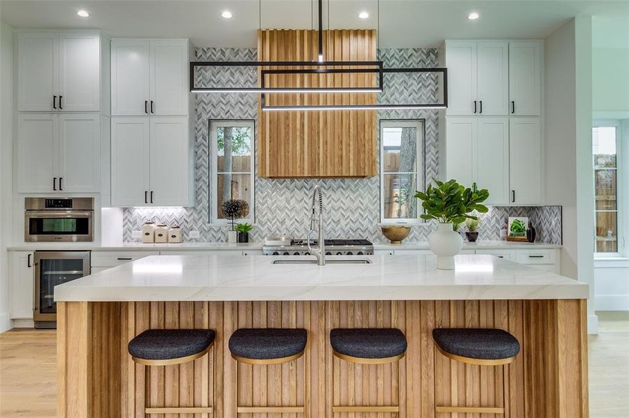 Kitchen with plenty of natural light, light hardwood / wood-style flooring, light stone countertops, and beverage cooler