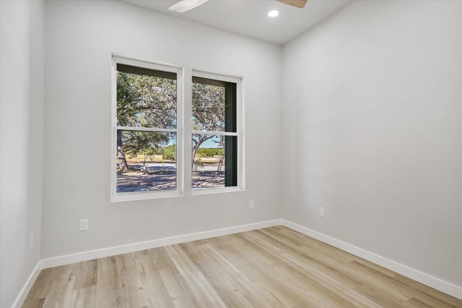 A well-lit room showcases durable laminate flooring, offering serene views of the outdoors through dual windows.