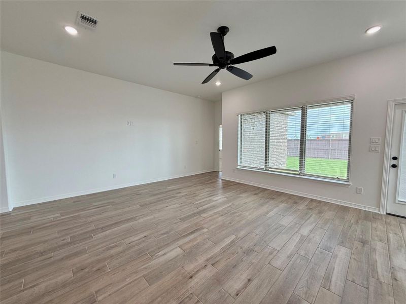 Spacious room featuring wood-finish plank flooring, a contemporary black ceiling fan, and recessed lighting
