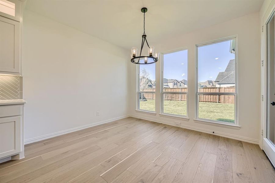 Unfurnished dining area featuring a notable chandelier, light hardwood / wood-style floors, and a healthy amount of sunlight