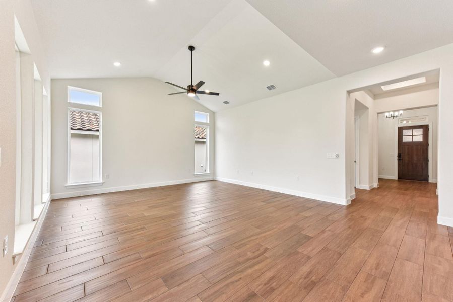 Unfurnished living room with light wood-style floors, recessed lighting, plenty of natural light, lofted ceiling, and a ceiling fan
