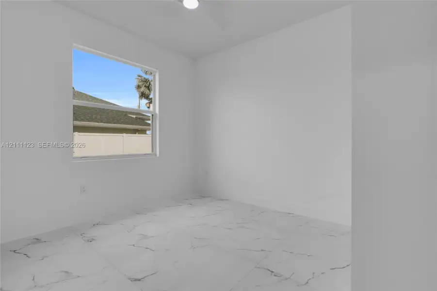 Bedroom with natural light and porcelain tile flooring.