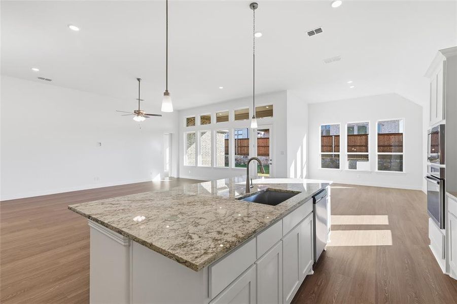 Kitchen with open floor plan, white cabinets, dark wood-style floors, light stone countertops, and recessed lighting Kitchen with open floor plan, white cabinets, dark wood-style floors, light stone countertops, and recessed lighting