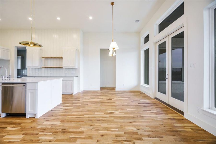 Kitchen with white cabinetry, dishwasher, pendant lighting, and light hardwood / wood-style floors