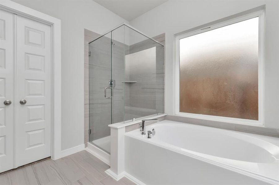 This additional view of the primary bath features a walk-in shower with the tile surround and separate garden tub perfect for soaking after a long day. Sample photo of completed home with similar floor plan. As-built interior colors and selections may vary.