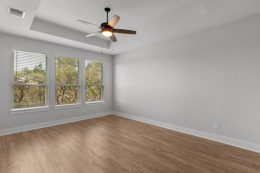 A well-lit bedroom features durable wood flooring and an integrated ceiling fan for comfort.
