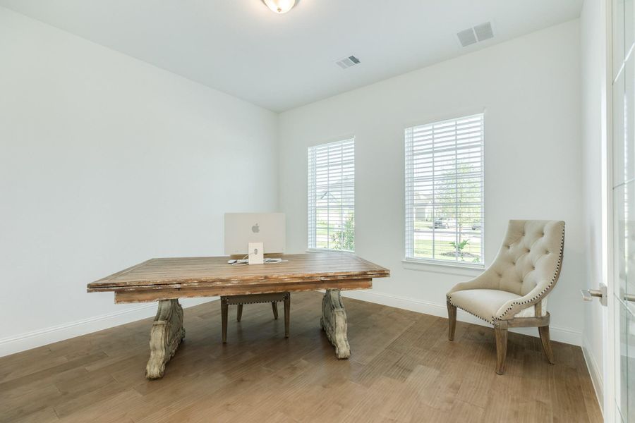 This office features a spacious floor plan, elegant wood flooring, and expansive windows that provide abundant natural light.