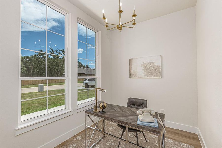 Dedicated space featuring two large grid-pattern windows, a modern chandelier, light-toned walls, and wood-finish flooring