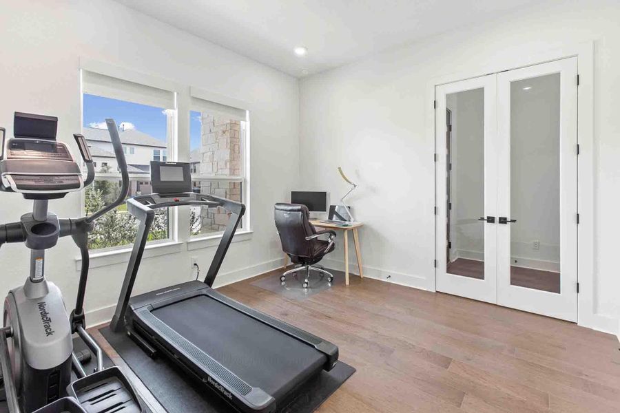 Spacious room featuring wood-finish flooring, white walls, and recessed lighting