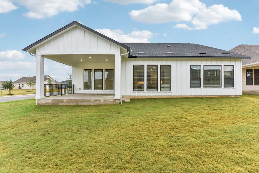 Back of property featuring board and batten siding, a patio, a lawn, and roof with shingles Back of property featuring board and batten siding, a patio, a lawn, and roof with shingles