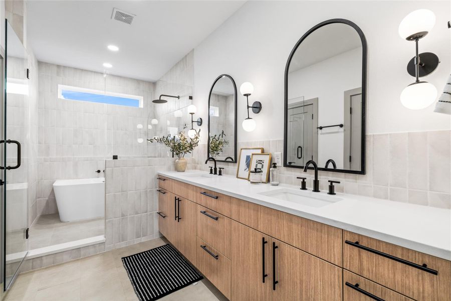 This spa-like primary bathroom blends contemporary luxury with timeless design—featuring a floating dual vanity with quartz counters, arched mirrors, matte black fixtures, and a frameless glass shower. A soaking tub tucked beneath a picture window completes the retreat, offering a perfect place to unwind in style. This spa-like primary bathroom blends contemporary luxury with timeless design—featuring a floating dual vanity with quartz counters, arched mirrors, matte black fixtures, and a frameless glass shower. A soaking tub tucked beneath a picture window completes the retreat, offering a perfect place to unwind in style.