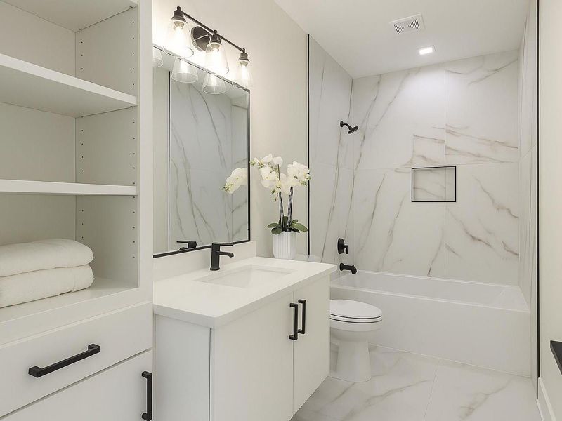 Stylish secondary bathroom featuring modern fixtures, sleek vanity, and a tub/shower combo with elegant tile surround.