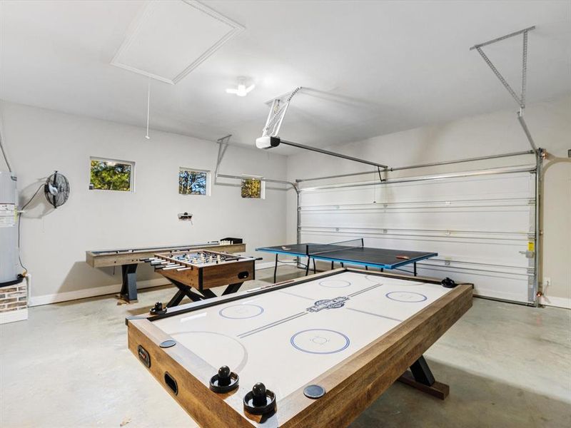 Playroom featuring attic access, finished concrete floors, water heater, and a garage