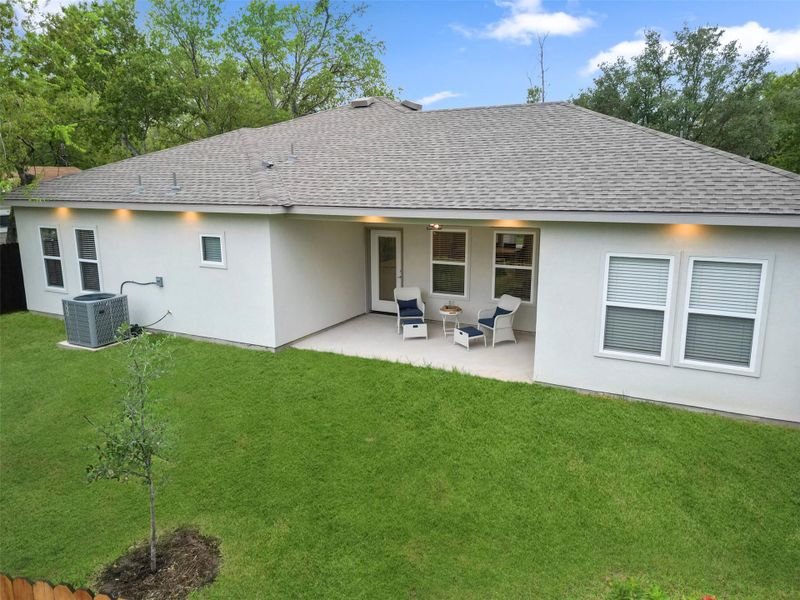 Rear view of property with a shingled roof, outdoor lounge area, stucco siding, a patio area, and a lawn Rear view of property with a shingled roof, outdoor lounge area, stucco siding, a patio area, and a lawn
