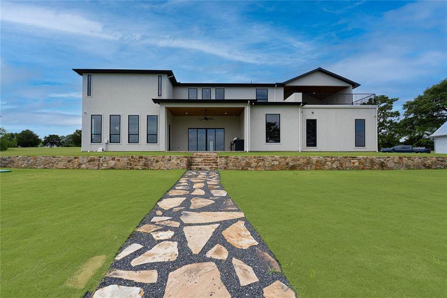 Modern home with a front lawn, ceiling fan, and stucco siding Modern home with a front lawn, ceiling fan, and stucco siding