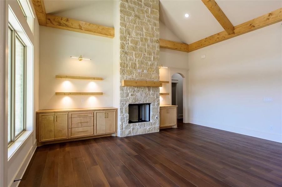 Unfurnished living room with a fireplace, dark wood-style floors, lofted ceiling, and arched walkways Unfurnished living room with a fireplace, dark wood-style floors, lofted ceiling, and arched walkways
