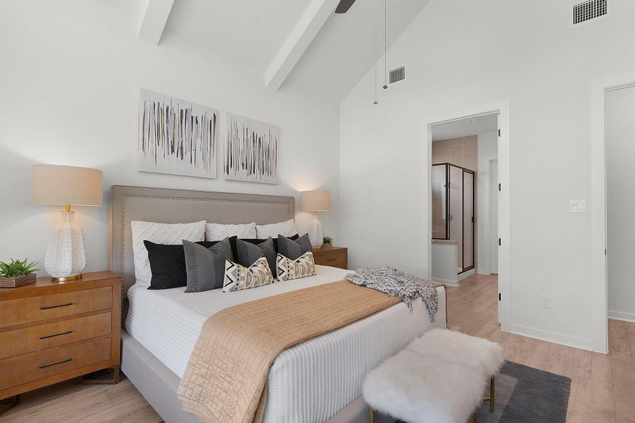 High vaulted ceilings with exposed beams elevate this serene bedroom featuring warm wood flooring.