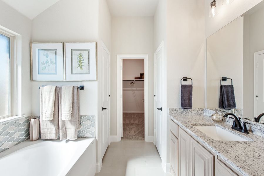 Master bathroom with soaking tub, granite double vanity, and walk-in closet entrance Master bathroom with soaking tub, granite double vanity, and walk-in closet entrance